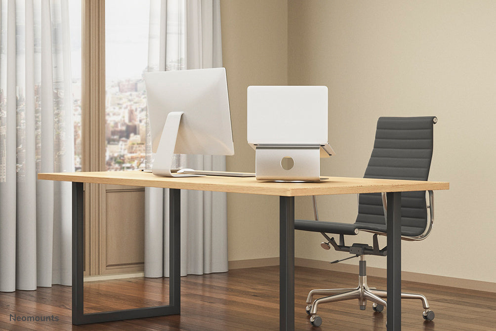 Neomounts NSLS050 ass en 360-Grad dréibare Büro-Stänner fir e Notebook.